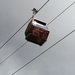 Low angle view of overhead cable car against sky