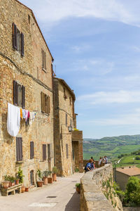 People on street amidst buildings in city against sky