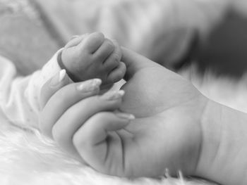 Cropped image of mother holding baby hand at home