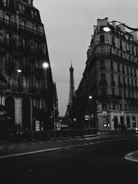 City street and buildings against sky at dusk