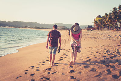 Man and woman walking along the beach at sunset in mexico