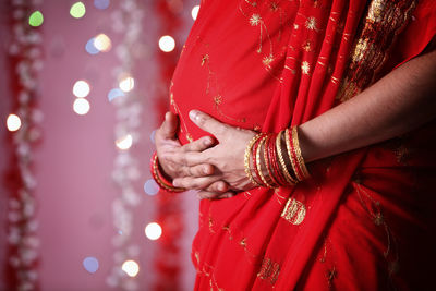 Midsection of pregnant woman in red sari during diwali