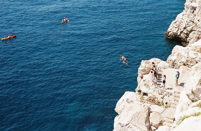 High angle view of people on cliff by sea