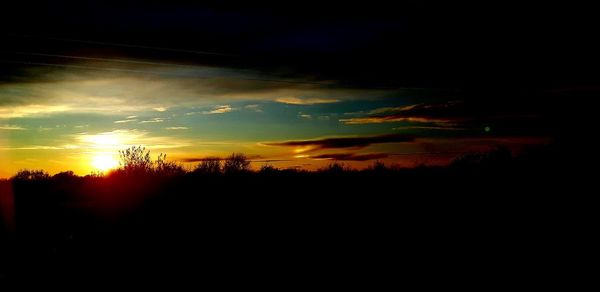 Silhouette landscape against dramatic sky during sunset