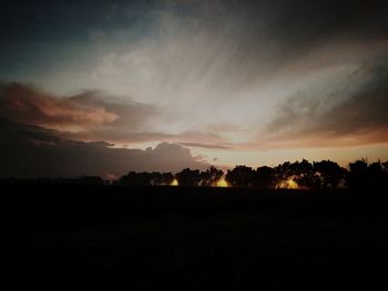 Silhouette trees on field against sky at sunset