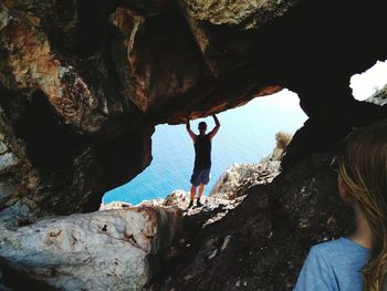 Rear view of friends on cliff against sea