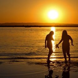 Silhouette of people on beach at sunset