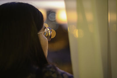 Rear view of woman looking through window