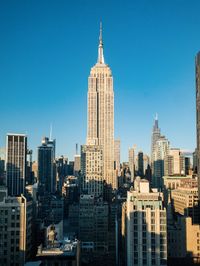 Modern buildings in city against clear blue sky