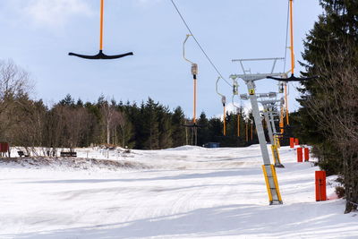 Ski lift over snow covered field against sky