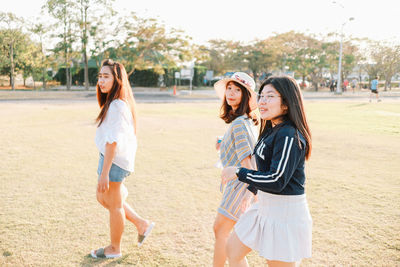 Full length of smiling young women standing in park