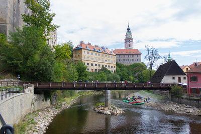 Bridge over river by buildings against sky