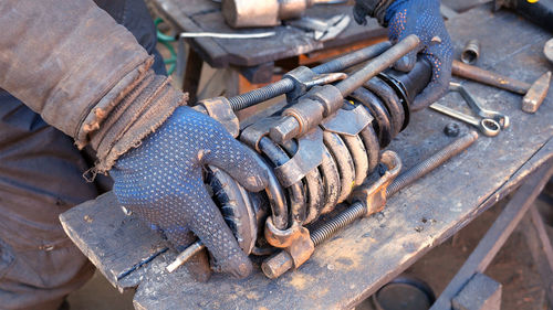 Cropped image of man holding shock absorber over wooden plank