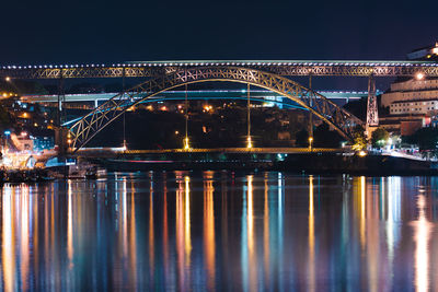 Illuminated bridge over river against sky at night