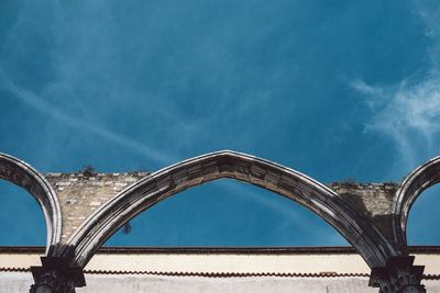 Low angle view of arch bridge against cloudy sky