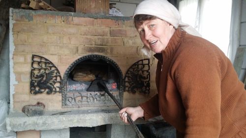 Portrait of woman baking bread in oven