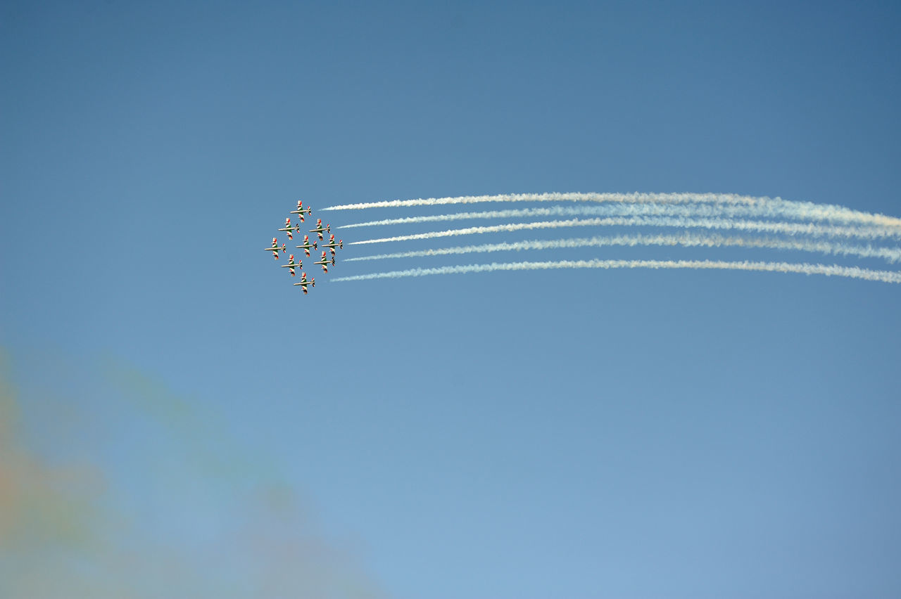 LOW ANGLE VIEW OF AIRSHOW AGAINST VAPOR TRAIL IN SKY