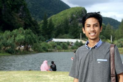 Portrait of a smiling young man standing against trees