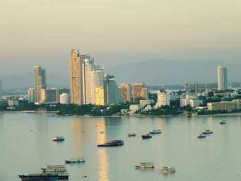 Boats in sea by buildings against sky in city