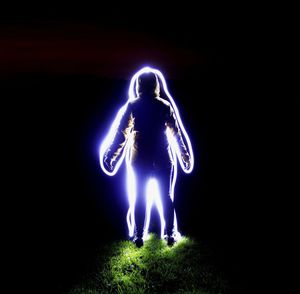 Man with illuminated light painting at night