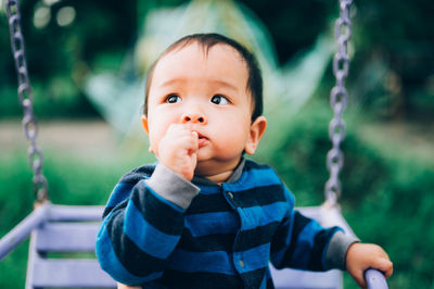 Portrait of cute boy sitting on swing