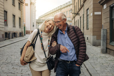 Happy retired senior couple with arm in arm strolling on city street