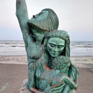 Statue on beach by sea against sky
