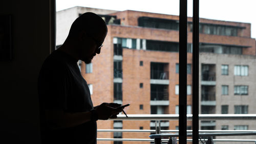 Side view of silhouette man standing against building in city