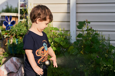 Little boy playing with a watering hose in the backyard