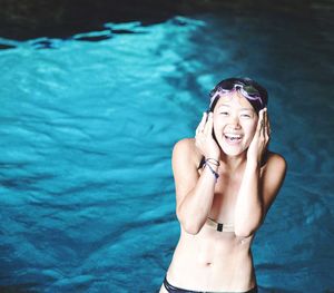 High angle view portrait of smiling woman standing by swimming pool