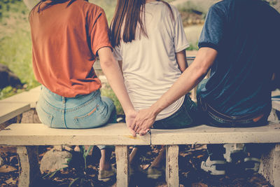 Rear view of friends sitting on bench at park