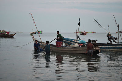 People fishing in sea against sky