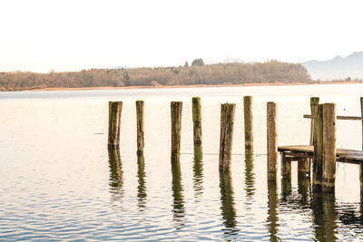 Wooden posts in lake against clear sky