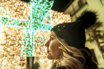 A young girl in a hat looking through christmas lights