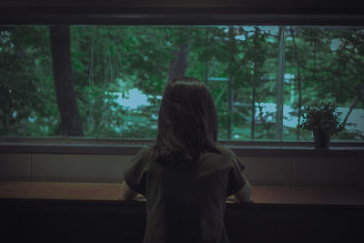 Rear view of woman looking through window