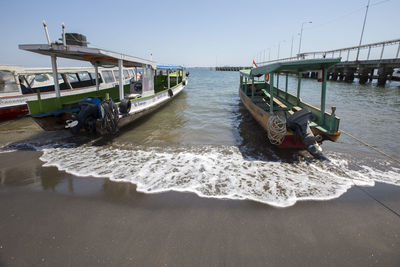 Boat moored on beach against clear sky