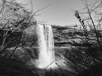 Scenic view of waterfall in forest against sky