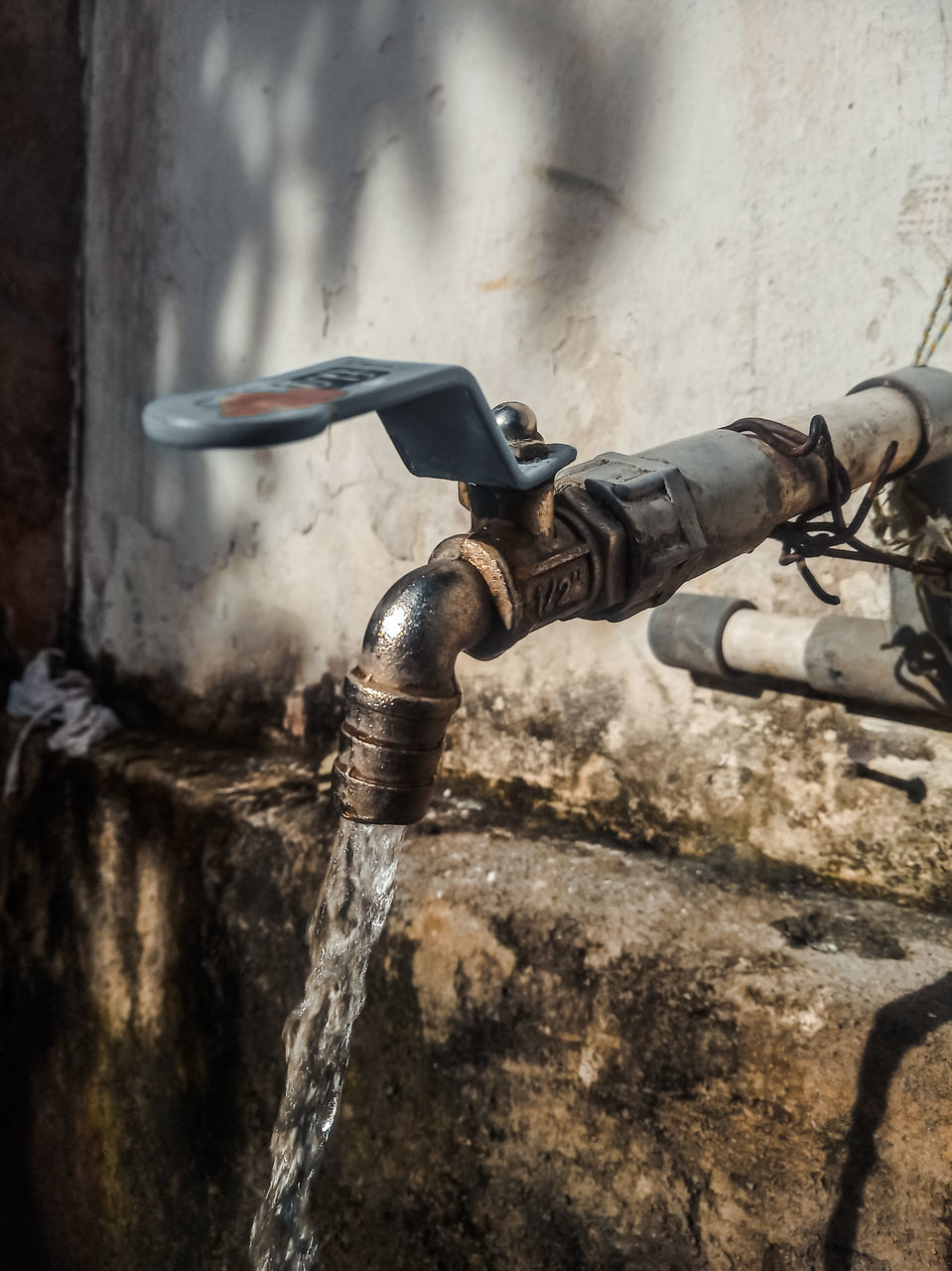 CLOSE-UP OF WATER FLOWING FROM PIPE AGAINST WALL