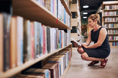 Woman reading book in public library. reading and learning. searching for literature. choosing book