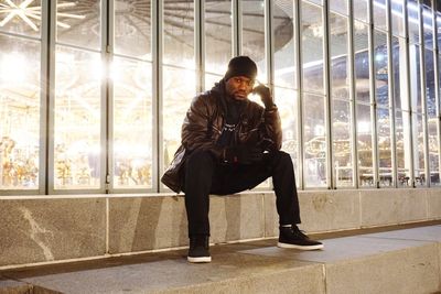 Full length of man sitting against window