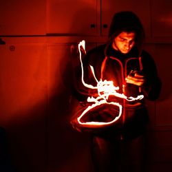 Close-up of mid adult man standing against illuminated wall