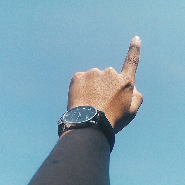 clear sky, blue, person, part of, low angle view, copy space, cropped, personal perspective, close-up, built structure, architecture, unrecognizable person, day, human finger, holding, sunlight, outdoors