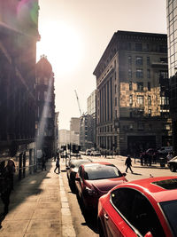 Cars on city street by buildings against sky