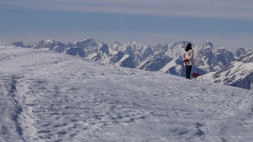 Rear view of person standing on snowcapped mountain against sky