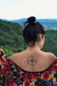 Rear view of young woman with tattoo on back standing against sky