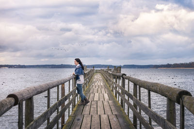 Man standing on pier over sea against sky