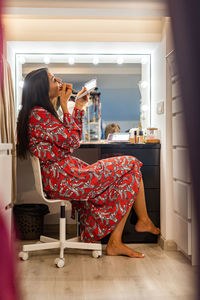 Young woman using phone while sitting on chair