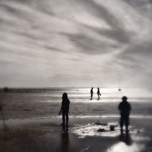 People walking on beach against sky