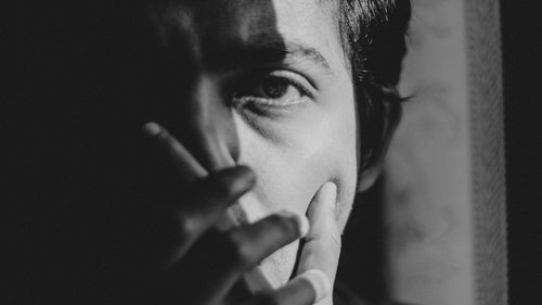 Close-up portrait of man with mouth covered by hands