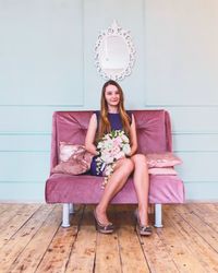 Portrait of smiling young woman sitting on wooden floor